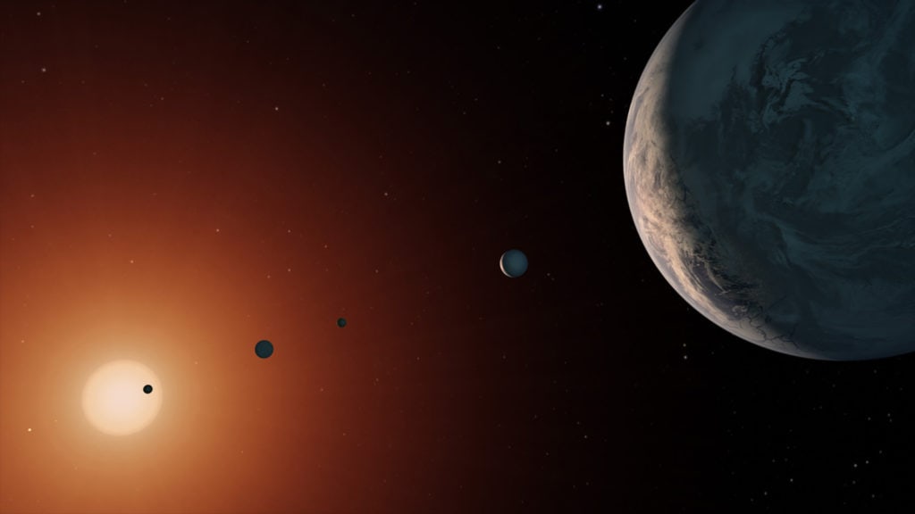 Een artistieke weergave van het TRAPPIST-1-systeem. vanuit het gezichtspunt van planeet TRAPPIST-1f, een grote planeet die helemaal rechts staat.  